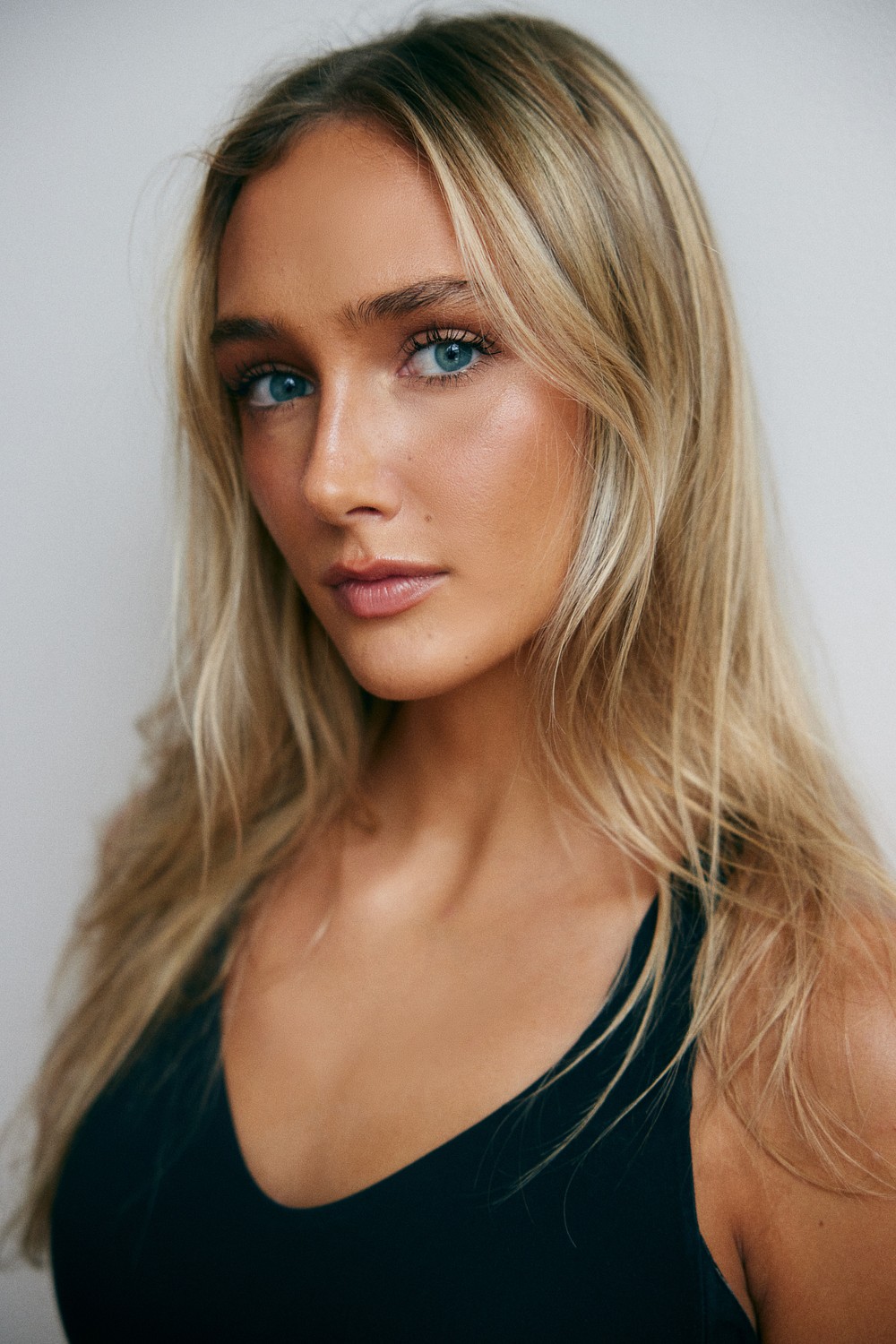 Portrait of Hannah in a black tank top, with soft lighting and a gentle expression, capturing her youthful and fresh look.